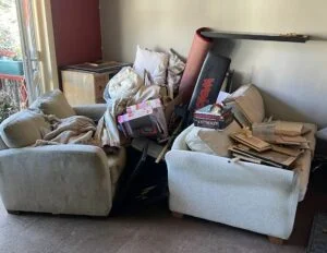 Example of WUDS (waste upholstered domestic seating) from a house clearance. Picture shows 2 sofas and a pile of junk.